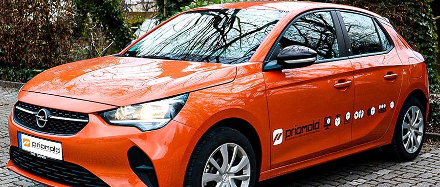 Ein oranges Auto mit dem priomold Logo