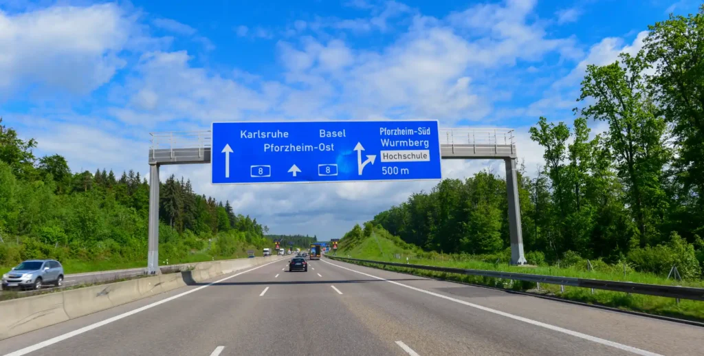 Deutsches Autobahnschild auf der A8: Karlsruhe, Basel, Pforzheim, Wurmberg, Hochschule, 500m. Verkehrsreiche Straße.